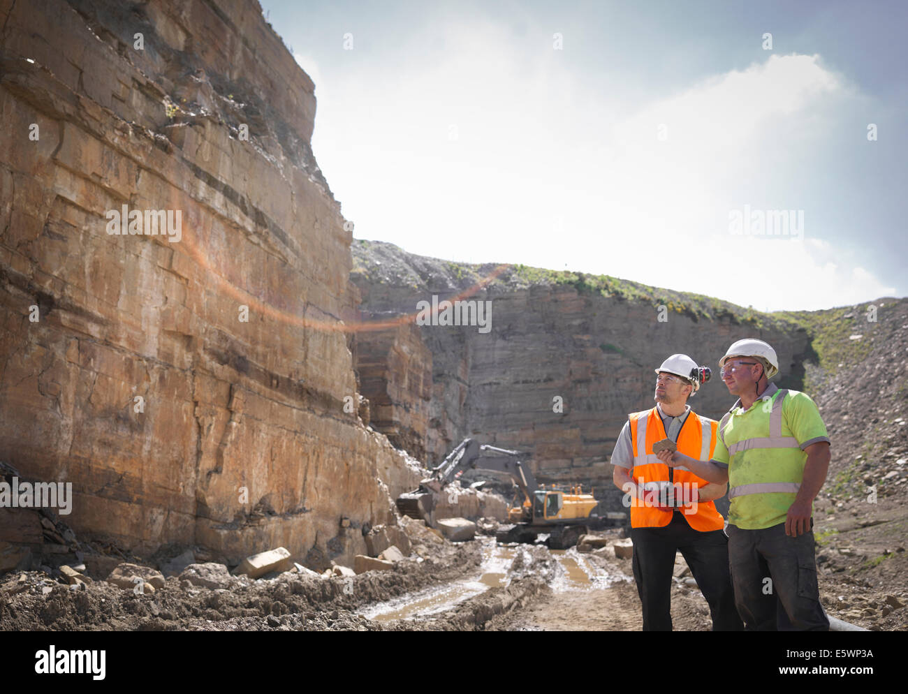 Quarry workers inspecting rock strata in stone quarry Stock Photo