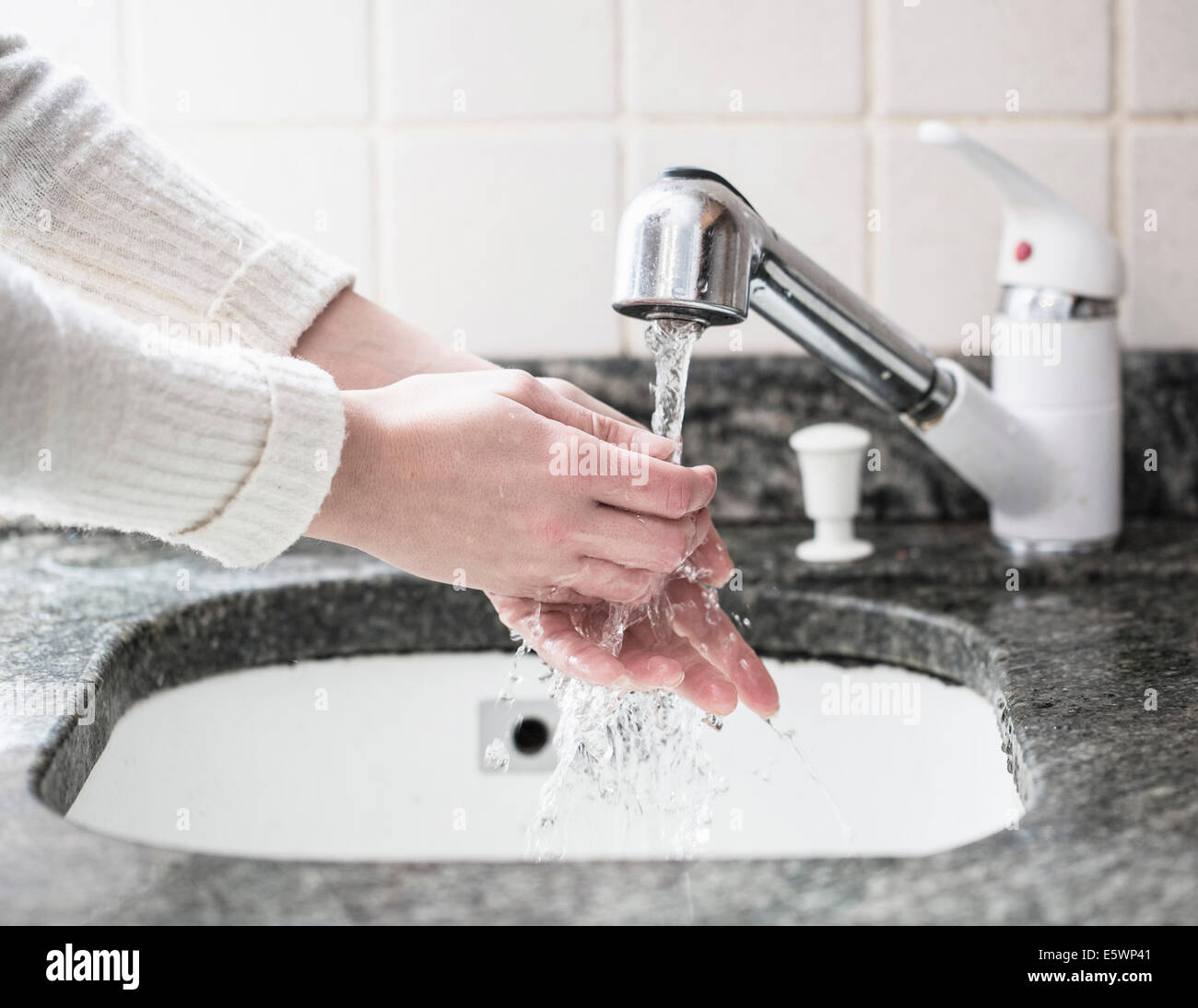 Cropped shot of young woman washing hands in sink Stock Photo