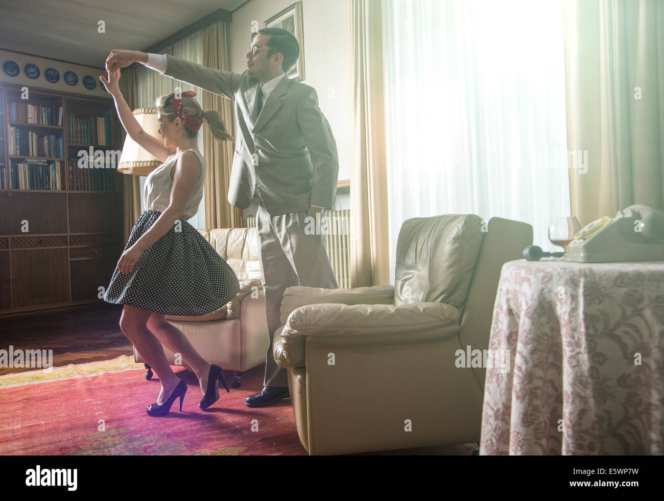 Young vintage couple dancing rock n roll in sitting room Stock Photo