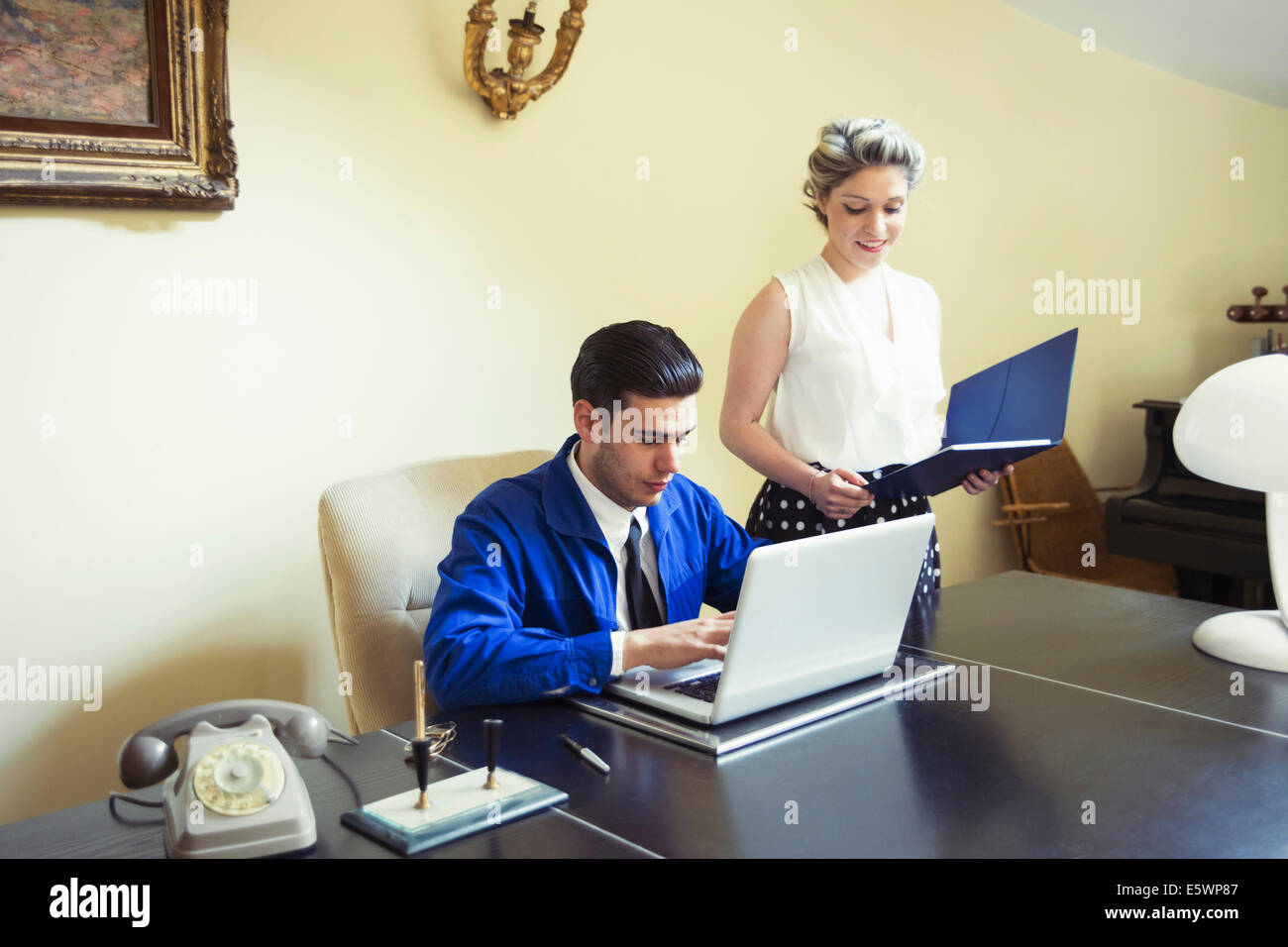 Young vintage couple at desk with files and laptop Stock Photo