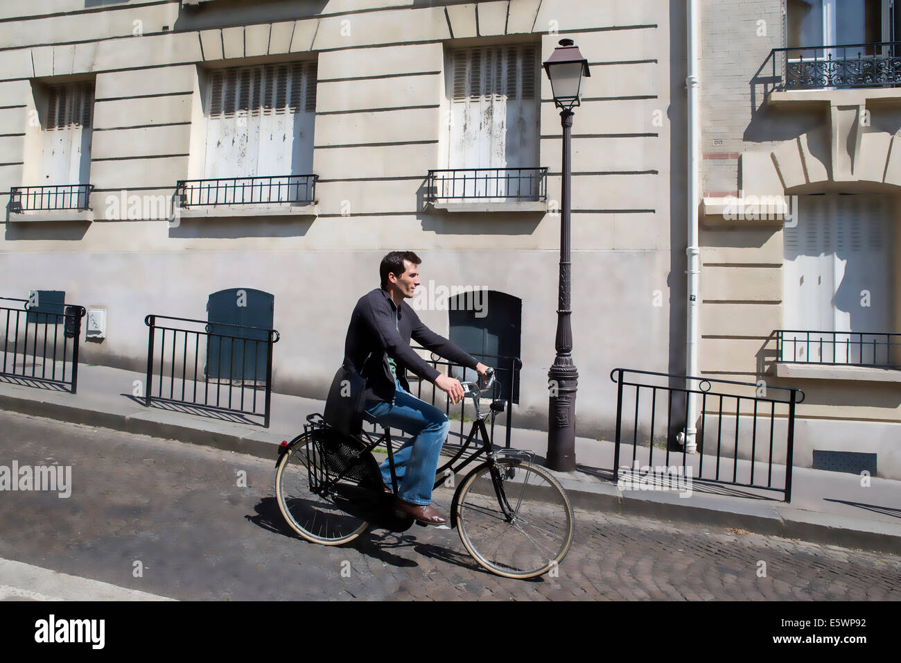 Mid adult man cycling down cobbled city street Stock Photo