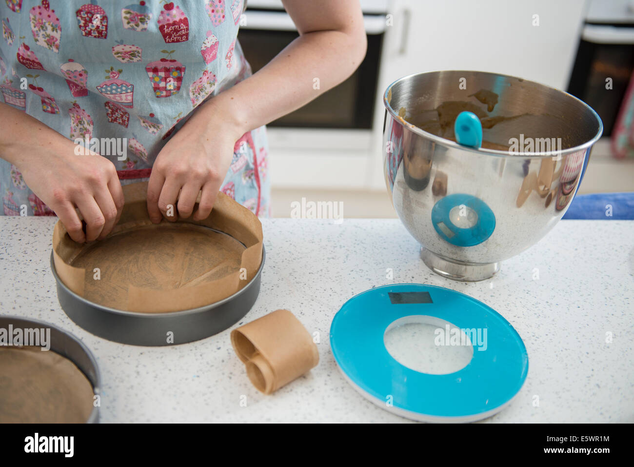 Female hands lining cake tins with greaseproof paper in bakery Stock