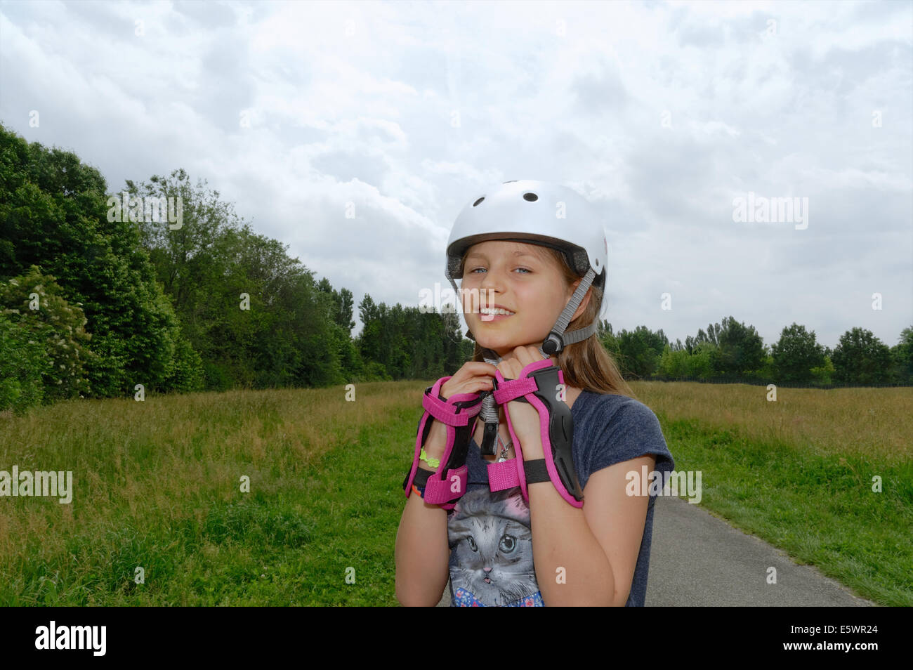 Portrait of rollerblading girl fastening skate helmet Stock Photo