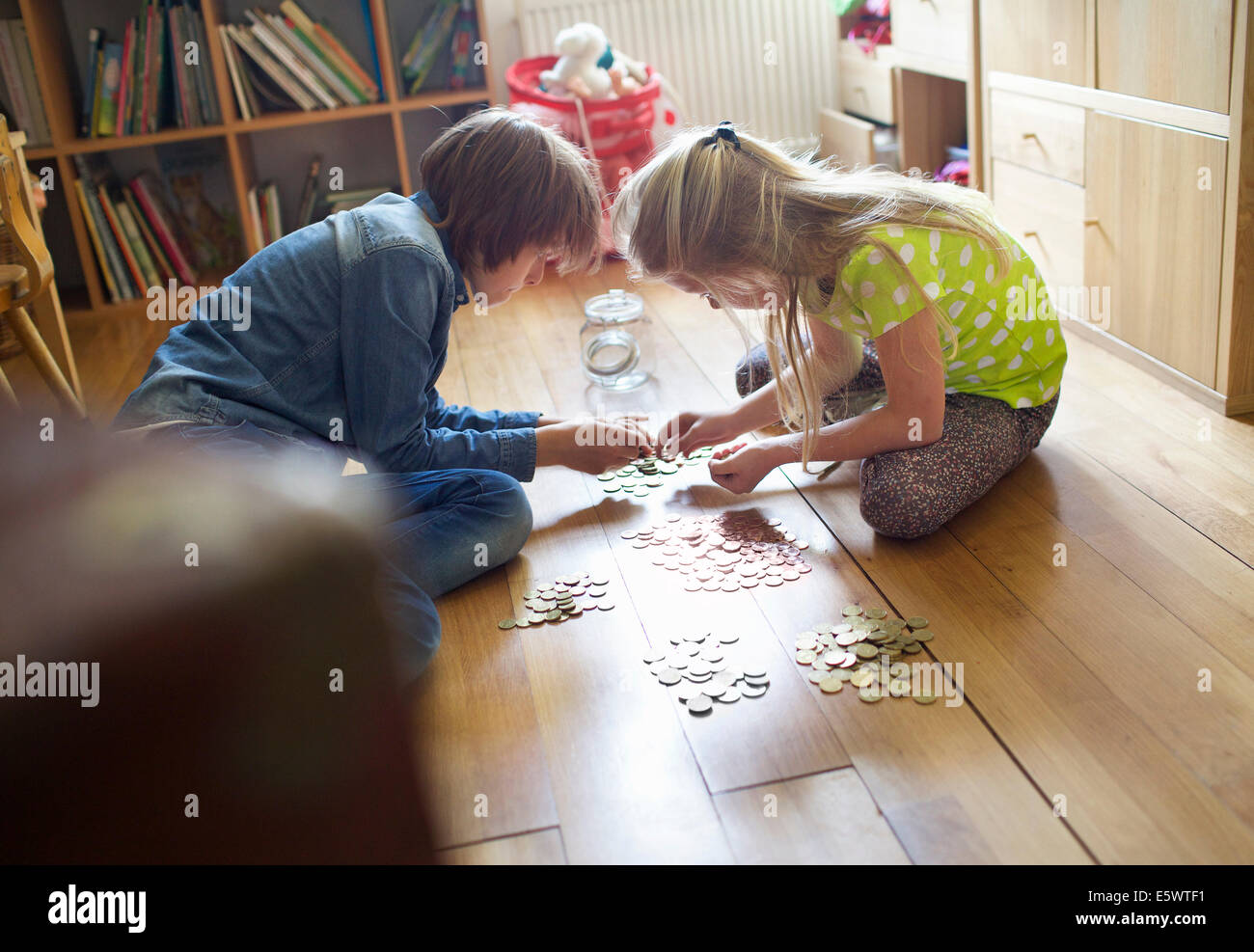 Brother and sister counting coins from savings jar Stock Photo