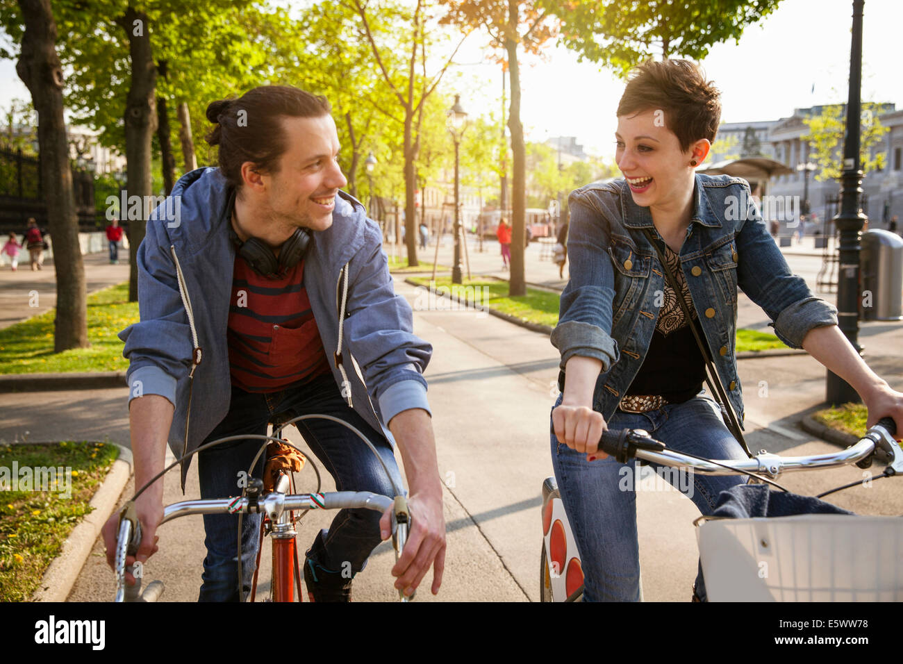 Young adult couple cycling through city, Vienna, Austria Stock Photo