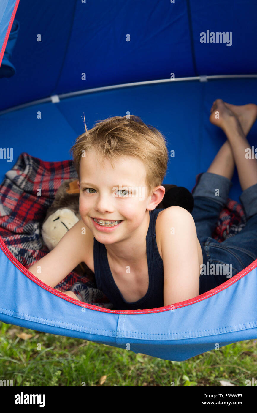 Portrait of smiling boy lying in tent suspended above grass Stock Photo