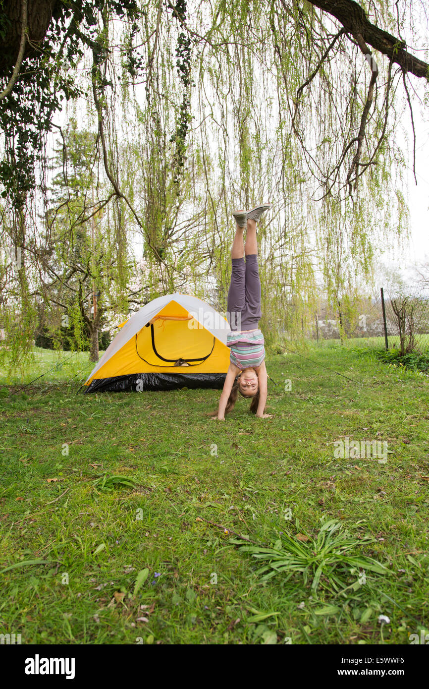 Smiling girl doing a handstand in garden Stock Photo