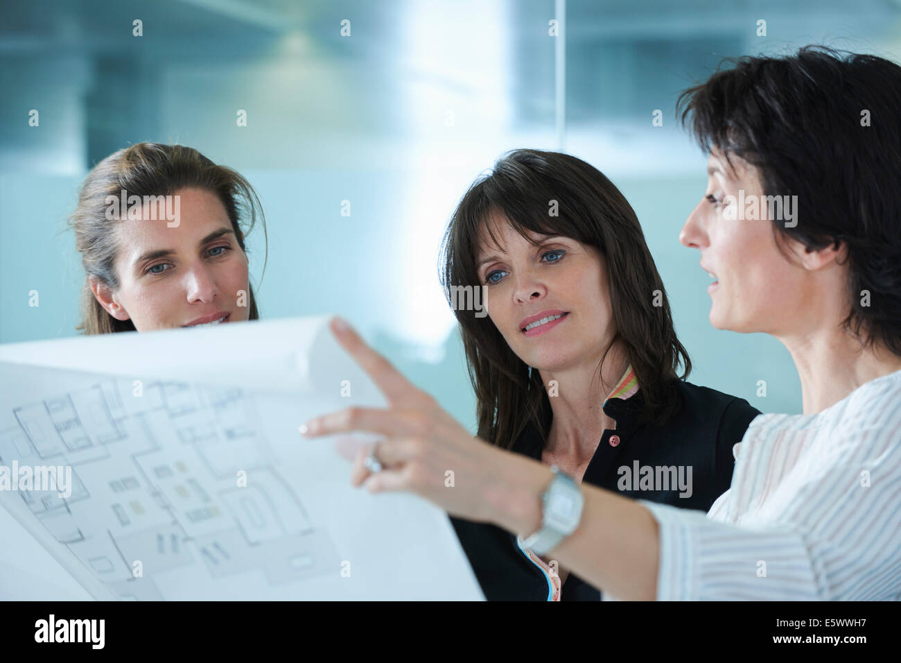 Architects holding up blueprints for client in office Stock Photo
