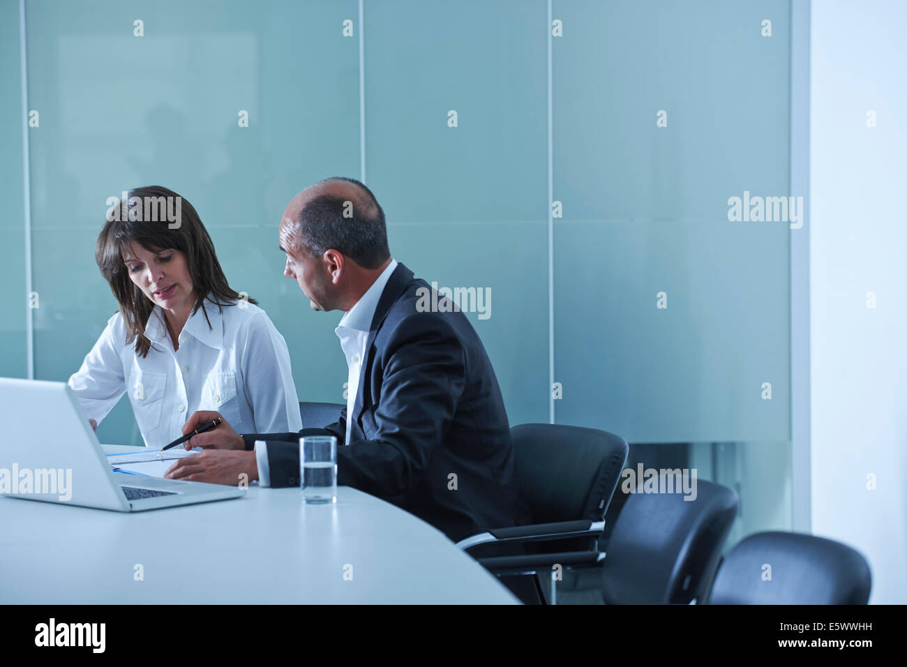 Businesswoman and man doing paperwork at boardroom table Stock Photo