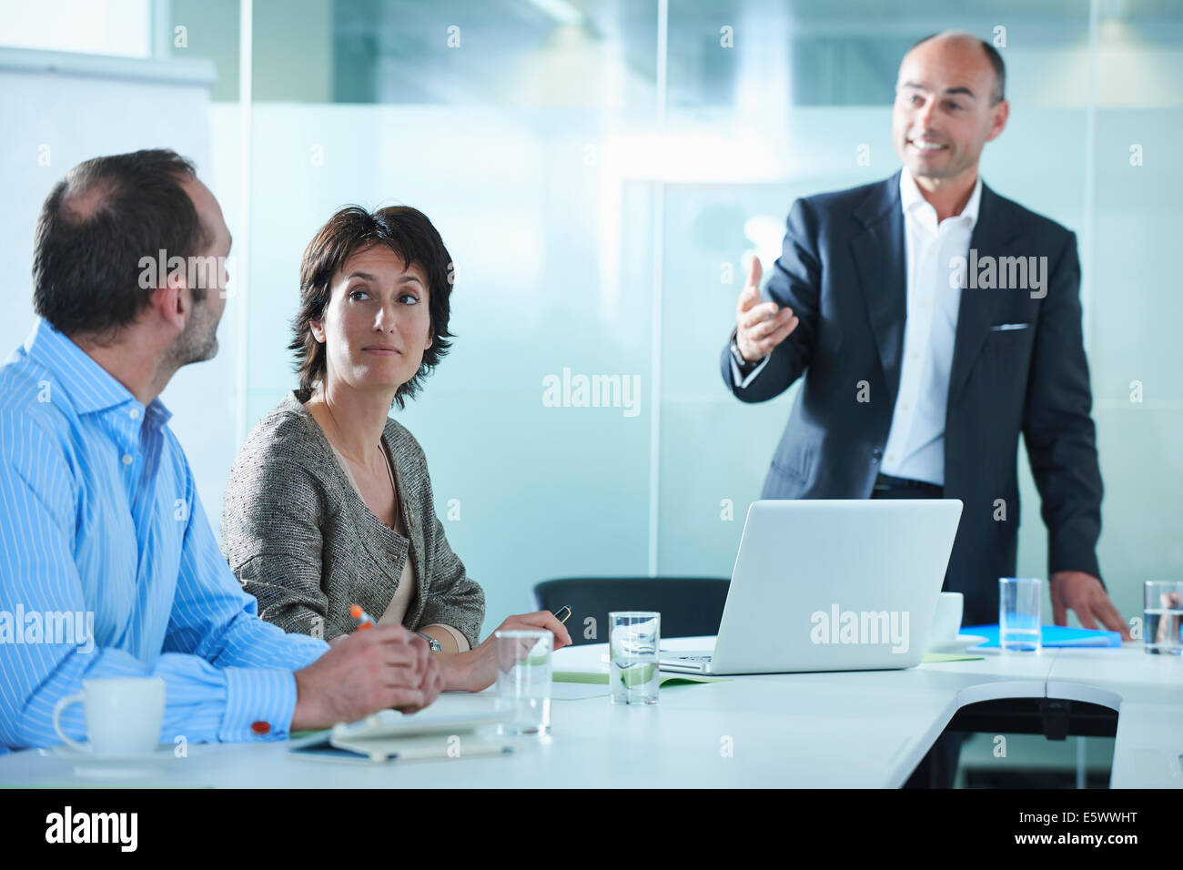 Businessmen and women arguing across boardroom table Stock Photo