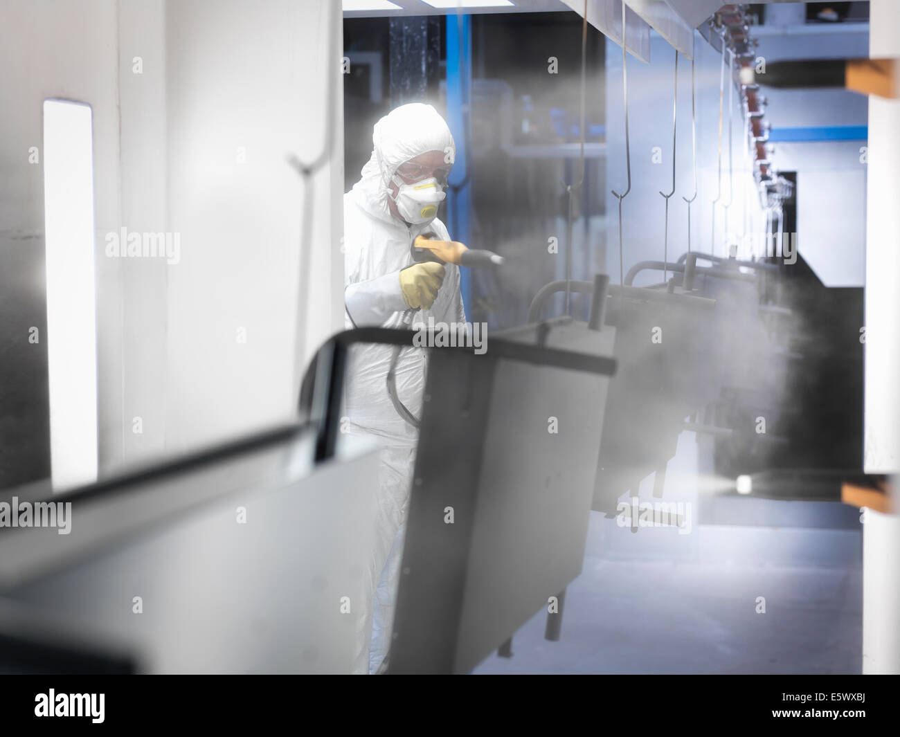 Worker powder coating parts in paint spray booth in sheet metal factory Stock Photo