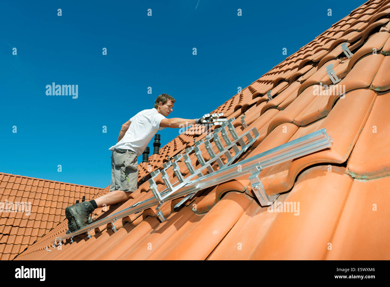 Worker installing framework for solar roof panels on new home, Netherlands Stock Photo