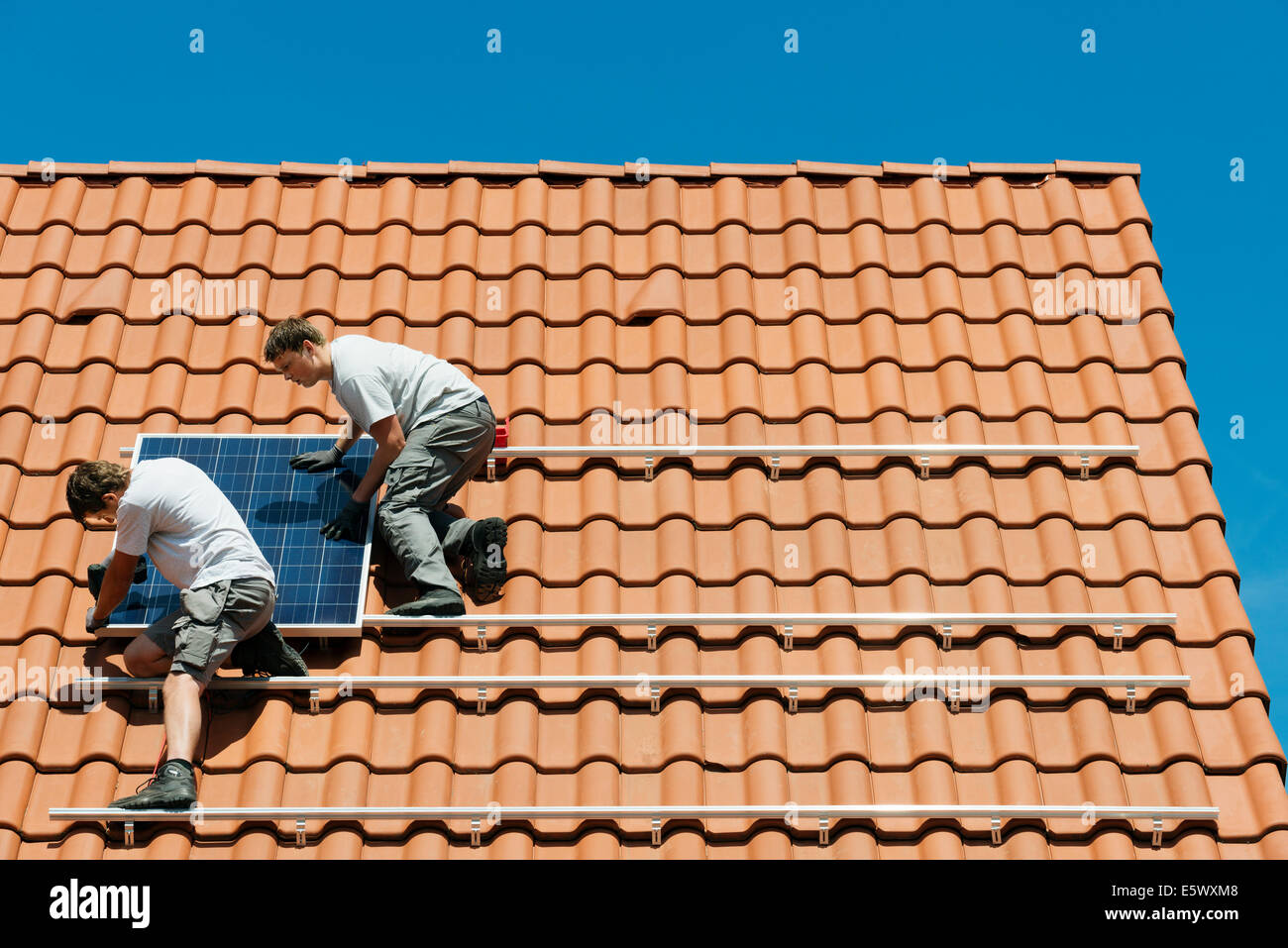 Workers installing solar panel on roof framework of new home