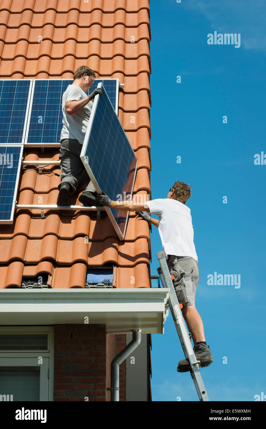 Workers installing solar panels on roof of new home, Netherlands Stock Photo