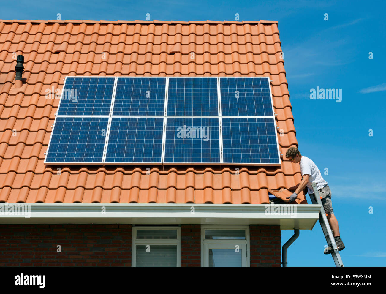 Worker checking installation of solar panels on roof of new home