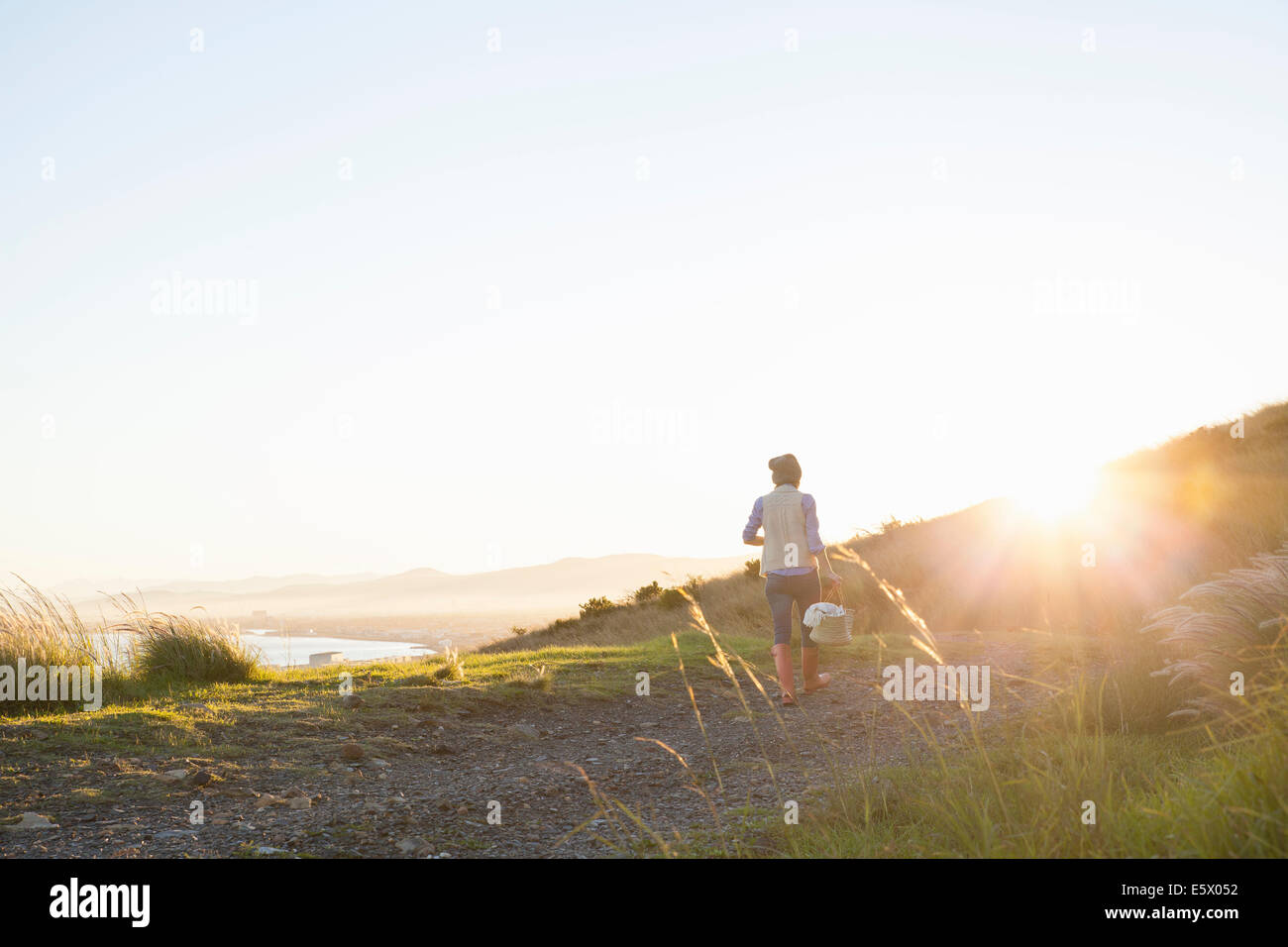 Young woman walking on hill at sunset Stock Photo