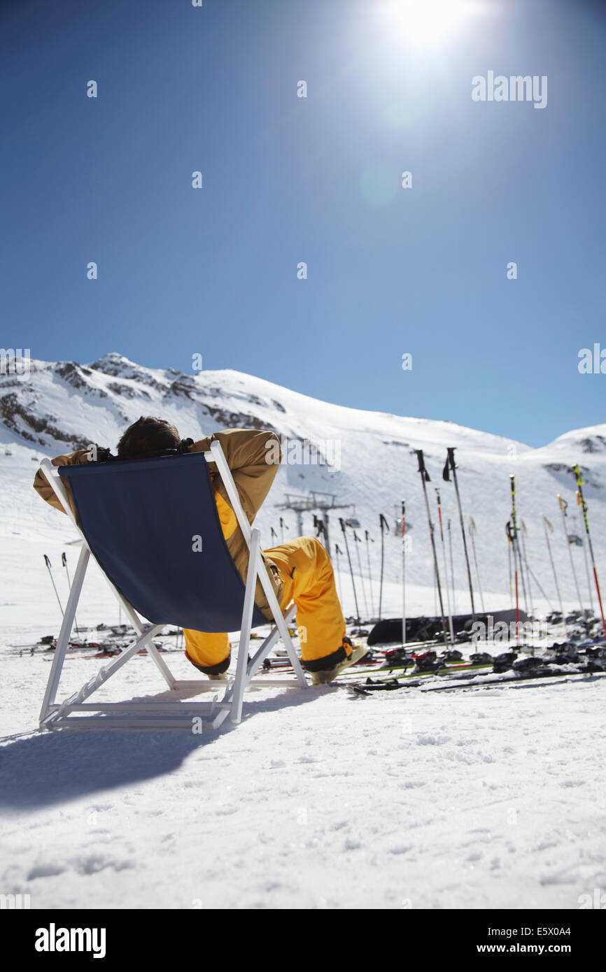 Rear view of mid adult male skier sitting on deck chair, Austria Stock Photo