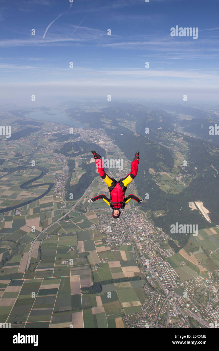 Female skydiver free falling upside down over Grenchen, Berne, Switzerland Stock Photo