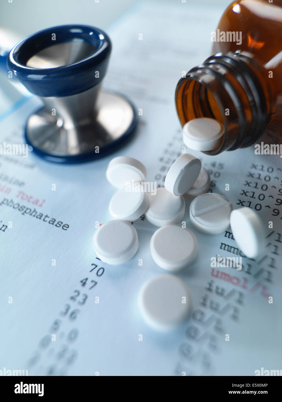 Stethoscope and pain killers pouring onto medical test results Stock Photo