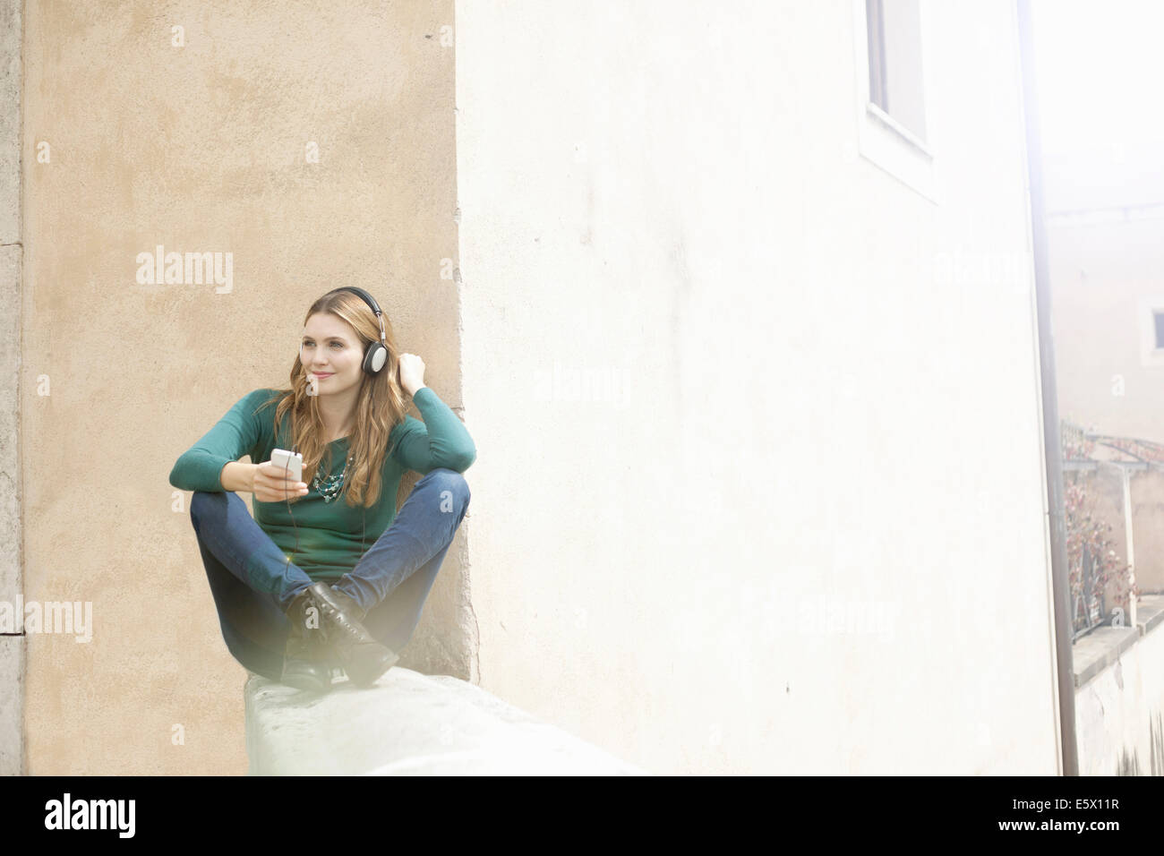 Young woman sitting cross legged listening to music through headphones Stock Photo