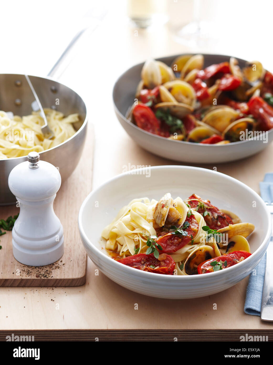 Bowls of fettucine clams with fresh tomatoes and herb garnish Stock Photo