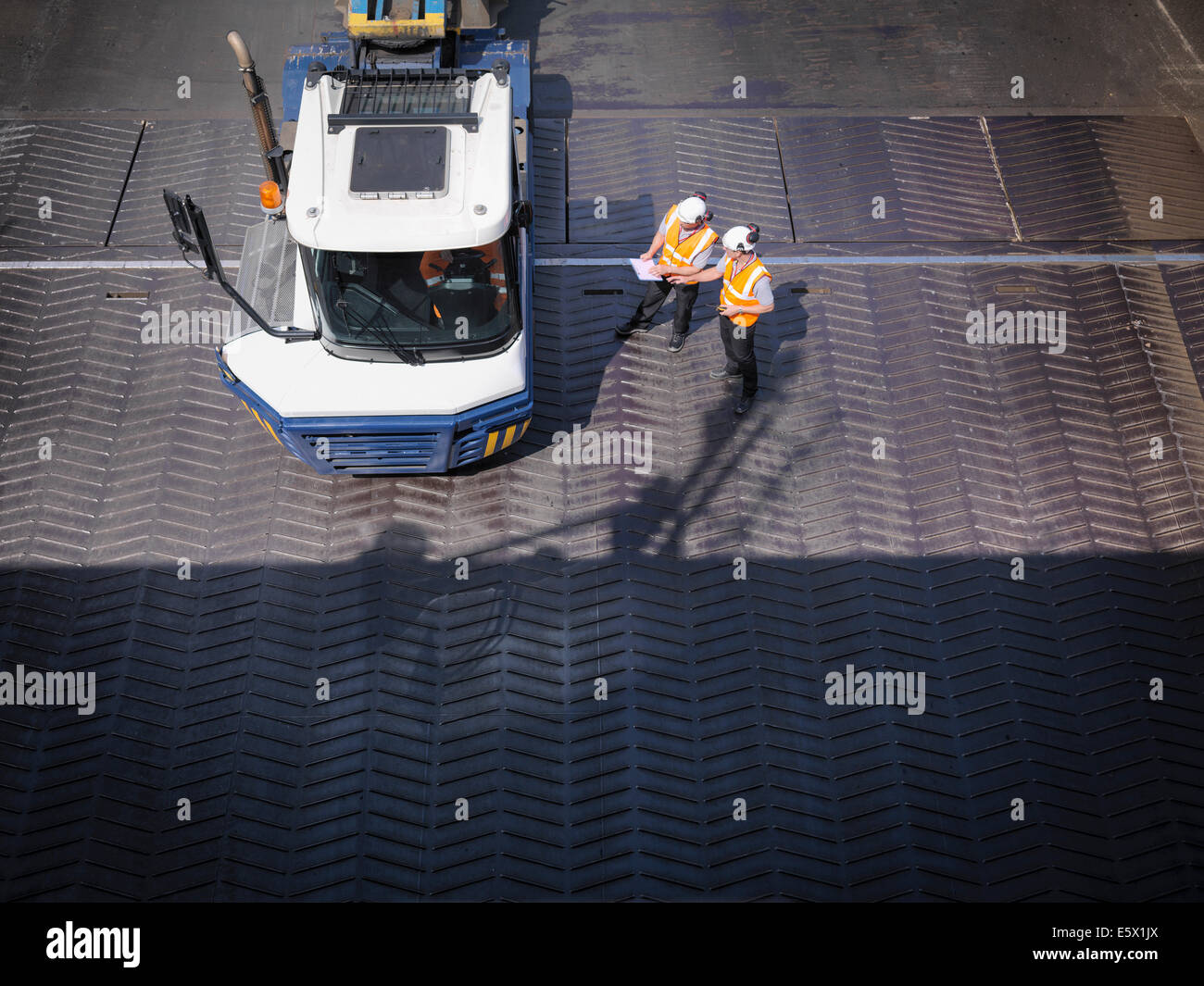 Workers in discussion with truck driver on ship's ramp, elevated view Stock Photo