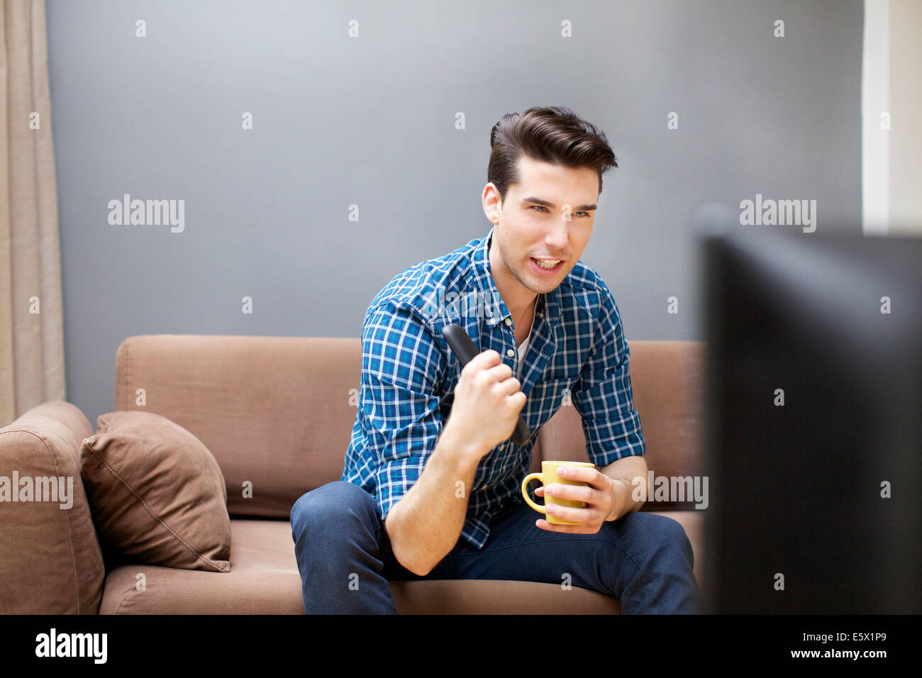 Young man watching TV in living room Stock Photo - Alamy