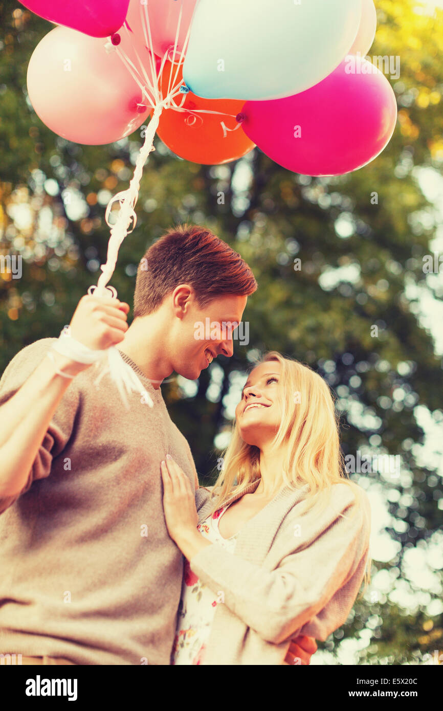smiling couple with colorful balloons in park Stock Photo