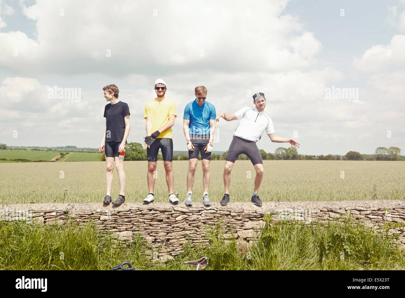 Cyclists standing on stone wall, Cotswolds, UK Stock Photo