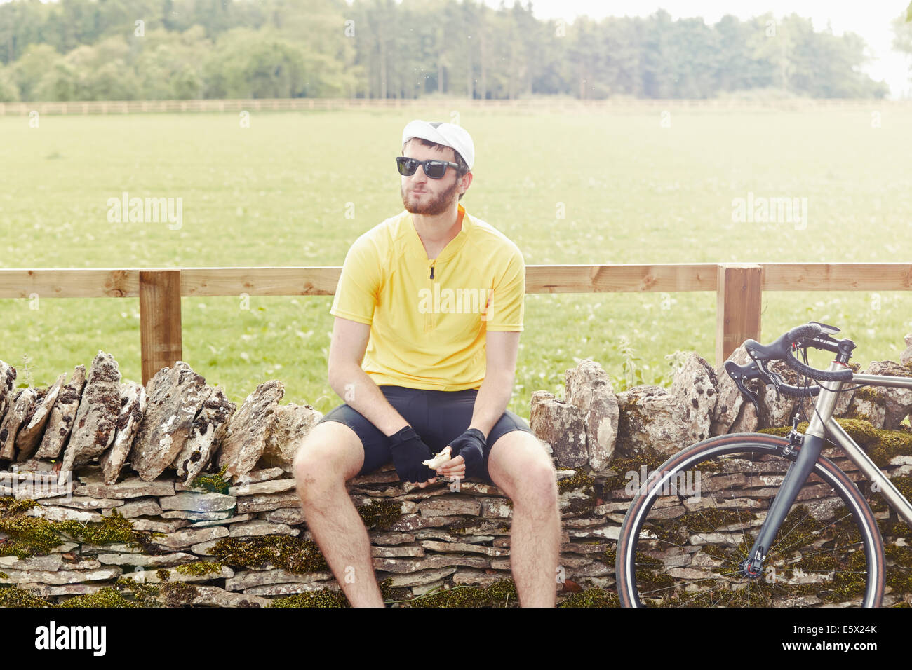 Cyclist sitting on stone wall, Cotswolds, UK Stock Photo