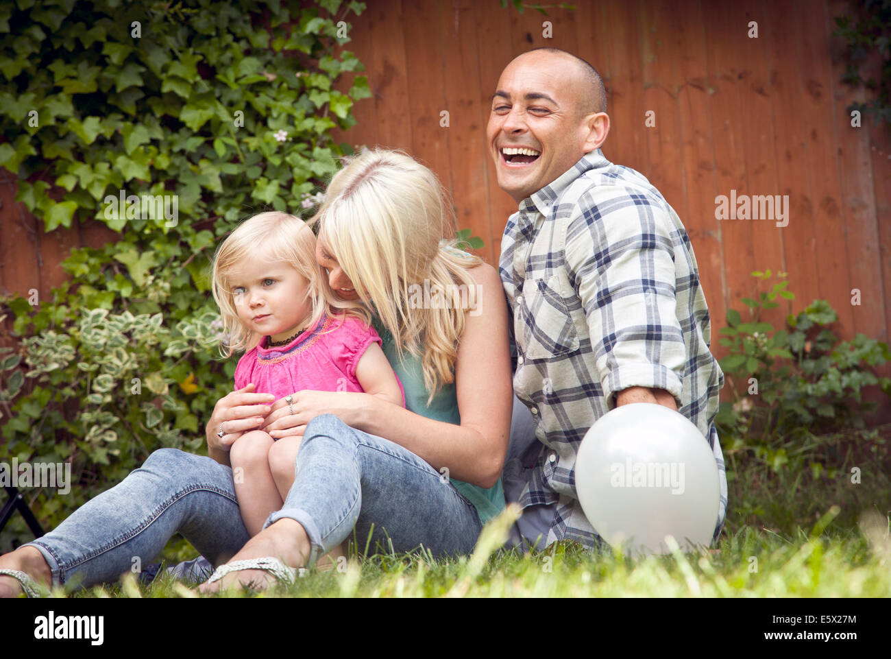 Happy couple sitting with toddler daughter in garden Stock Photo