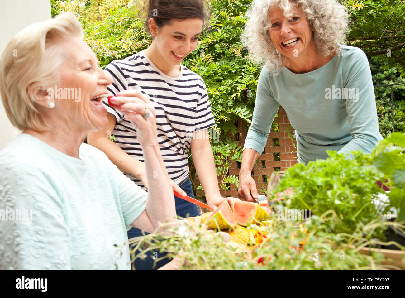 Three women preparing food at garden table Stock Photo