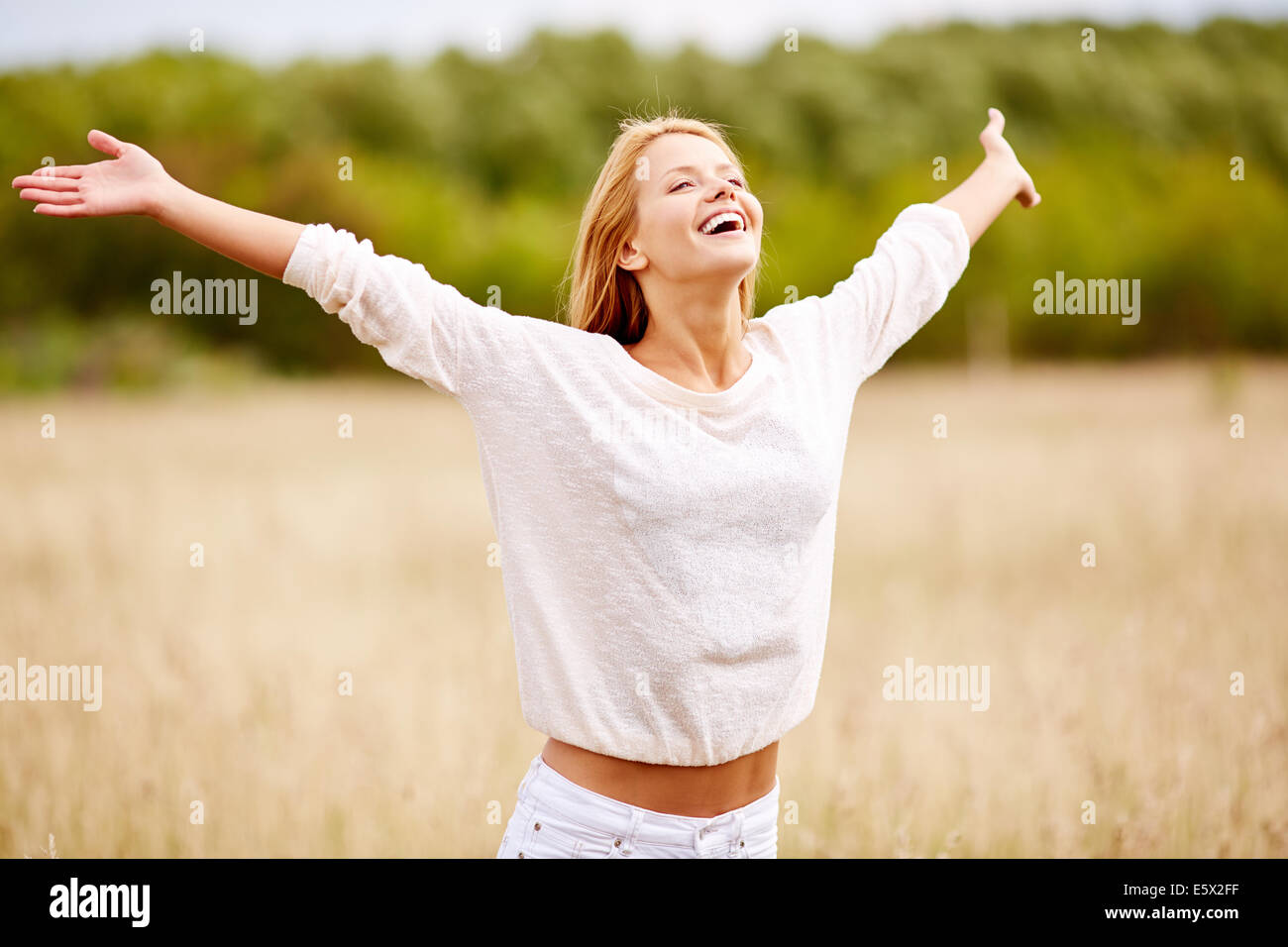 Image of happy woman with outstretched arms standing in field Stock Photo