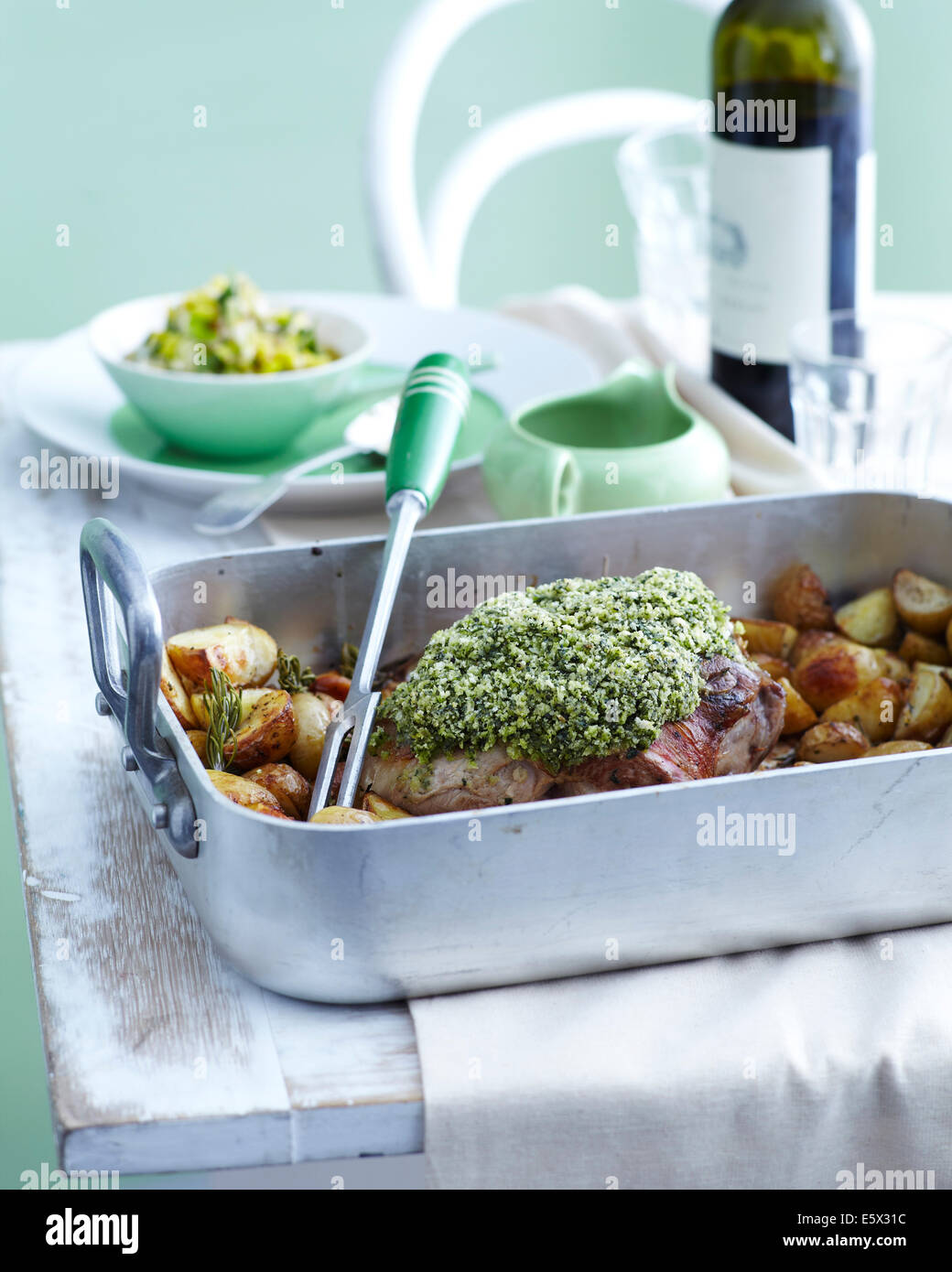 Roasting tray with roast lamb and potatoes with herb crust Stock Photo