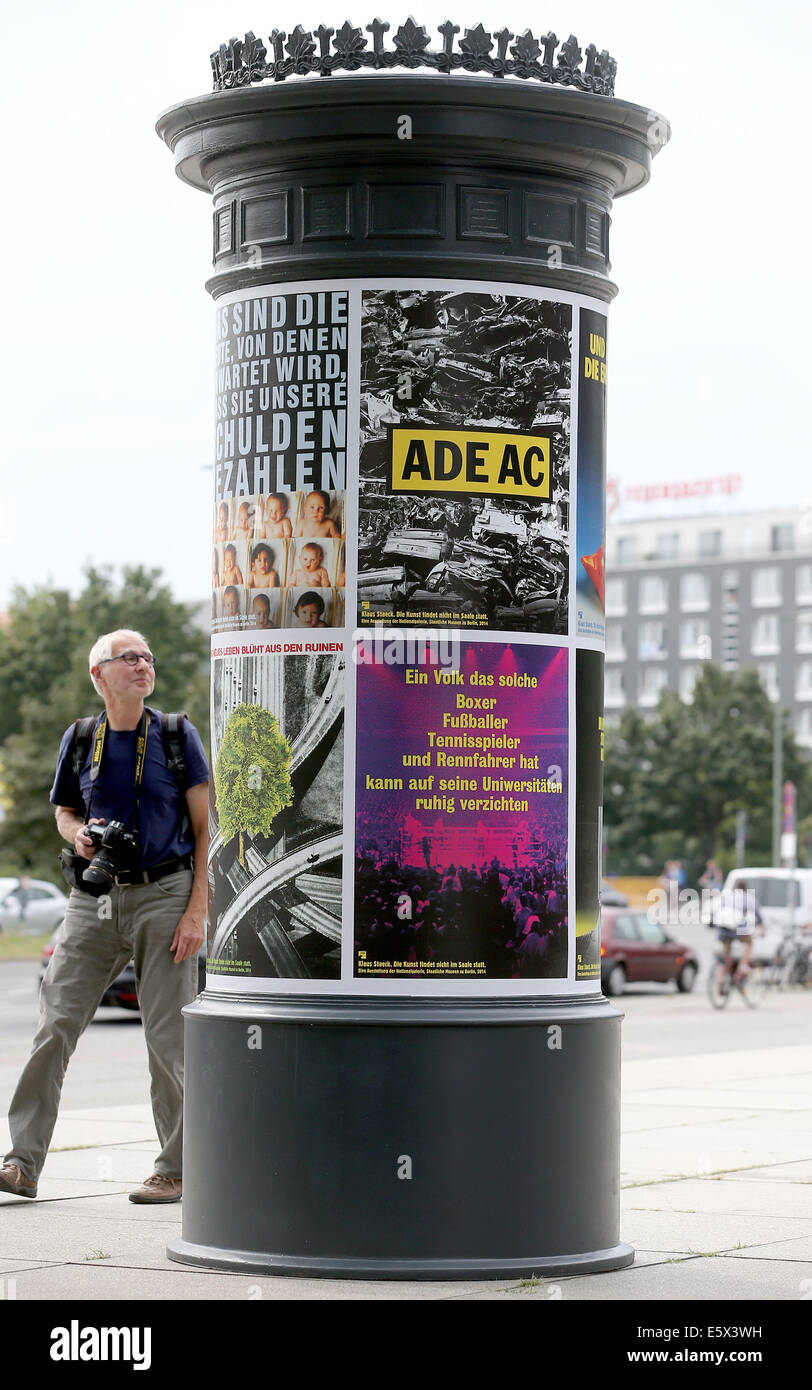 Berlin, Germany. 07th Aug, 2014. People walk past an advertising column  with Klaus Staeck's poster outside of the New National Gallery in Berlin,  Germany, 07 August 2014. His project "Die Kunst findet