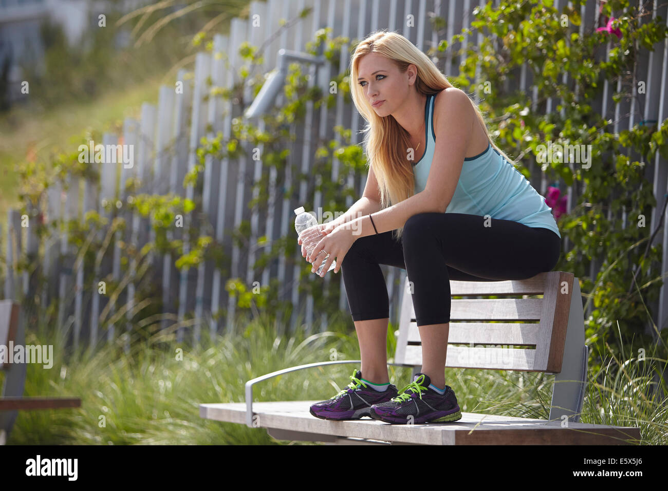 Woman sitting on top of park bench Stock Photo