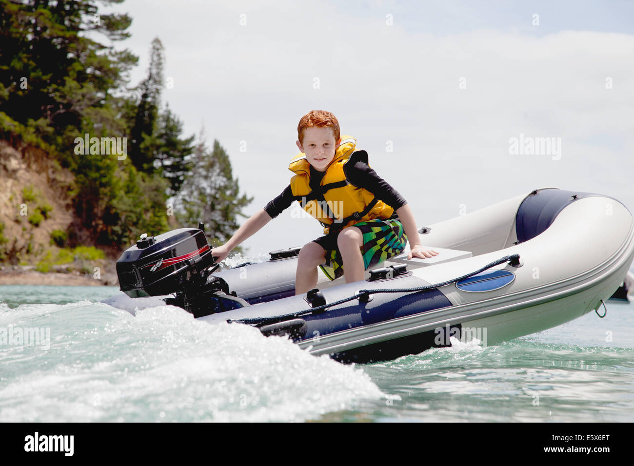 Boy steering speeding motor dinghy at sea Stock Photo