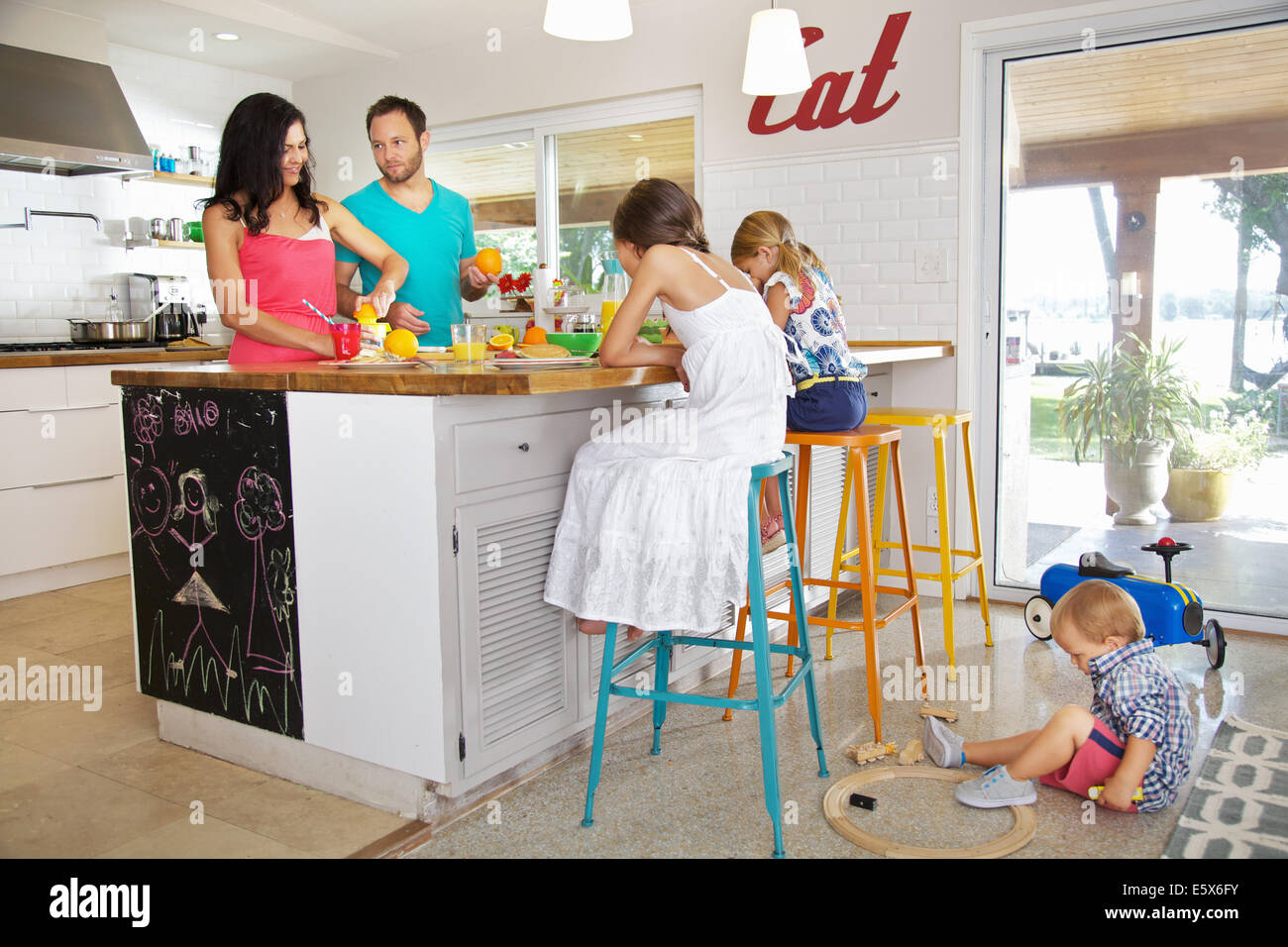 Mid adult parents and three children preparing breakfast in kitchen Stock Photo