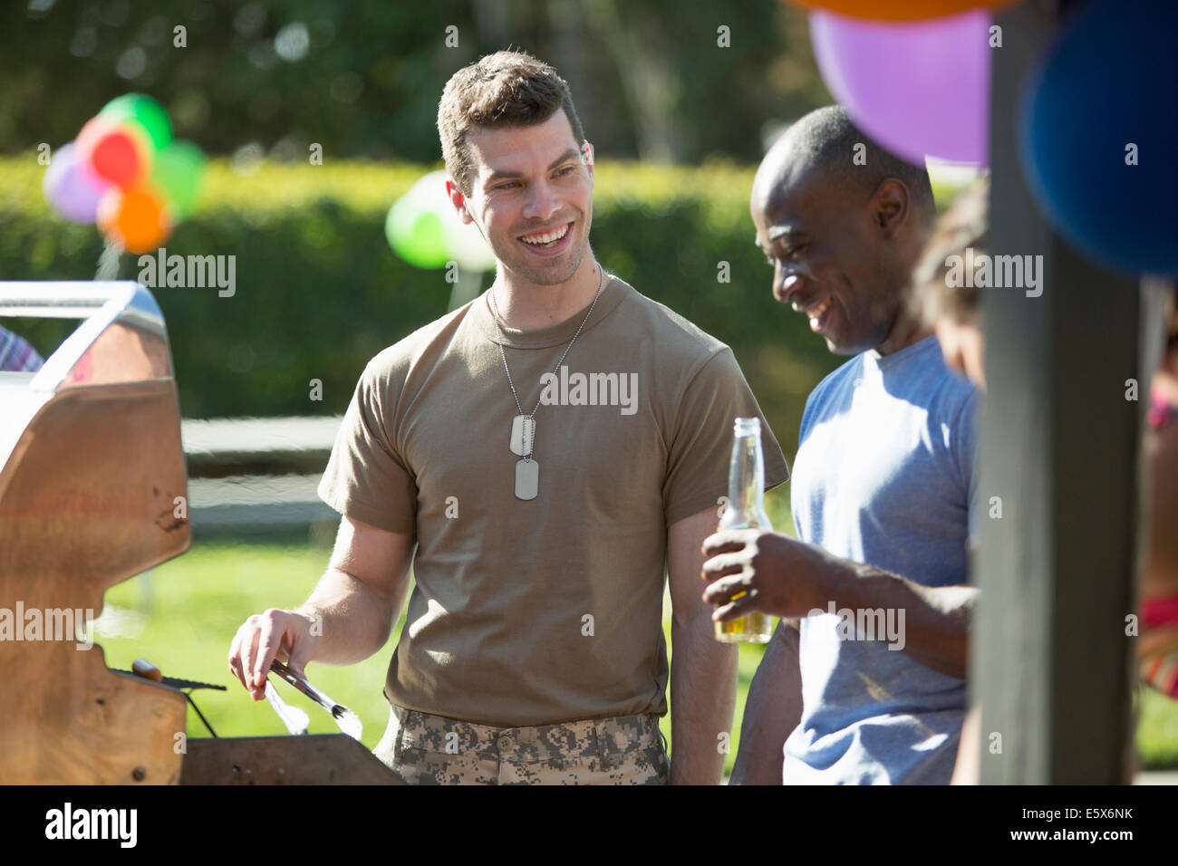 Male soldier barbecuing with friends at homecoming party Stock Photo