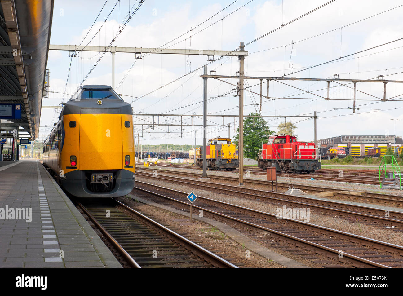 Yellow passenger train at empty platform of train station Stock Photo