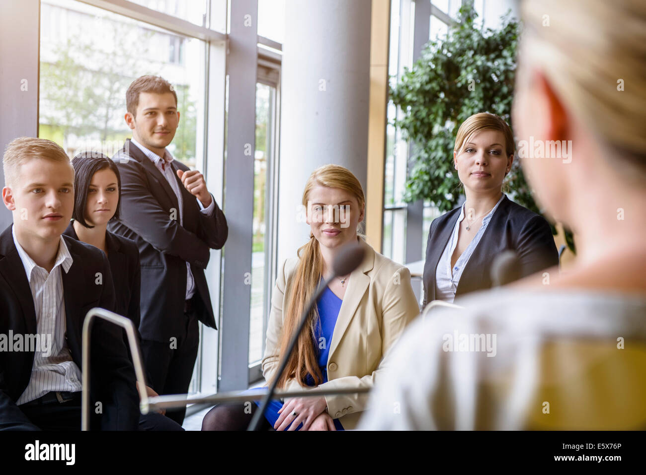 Businesswomen and men listening to speaker in office conference room Stock Photo