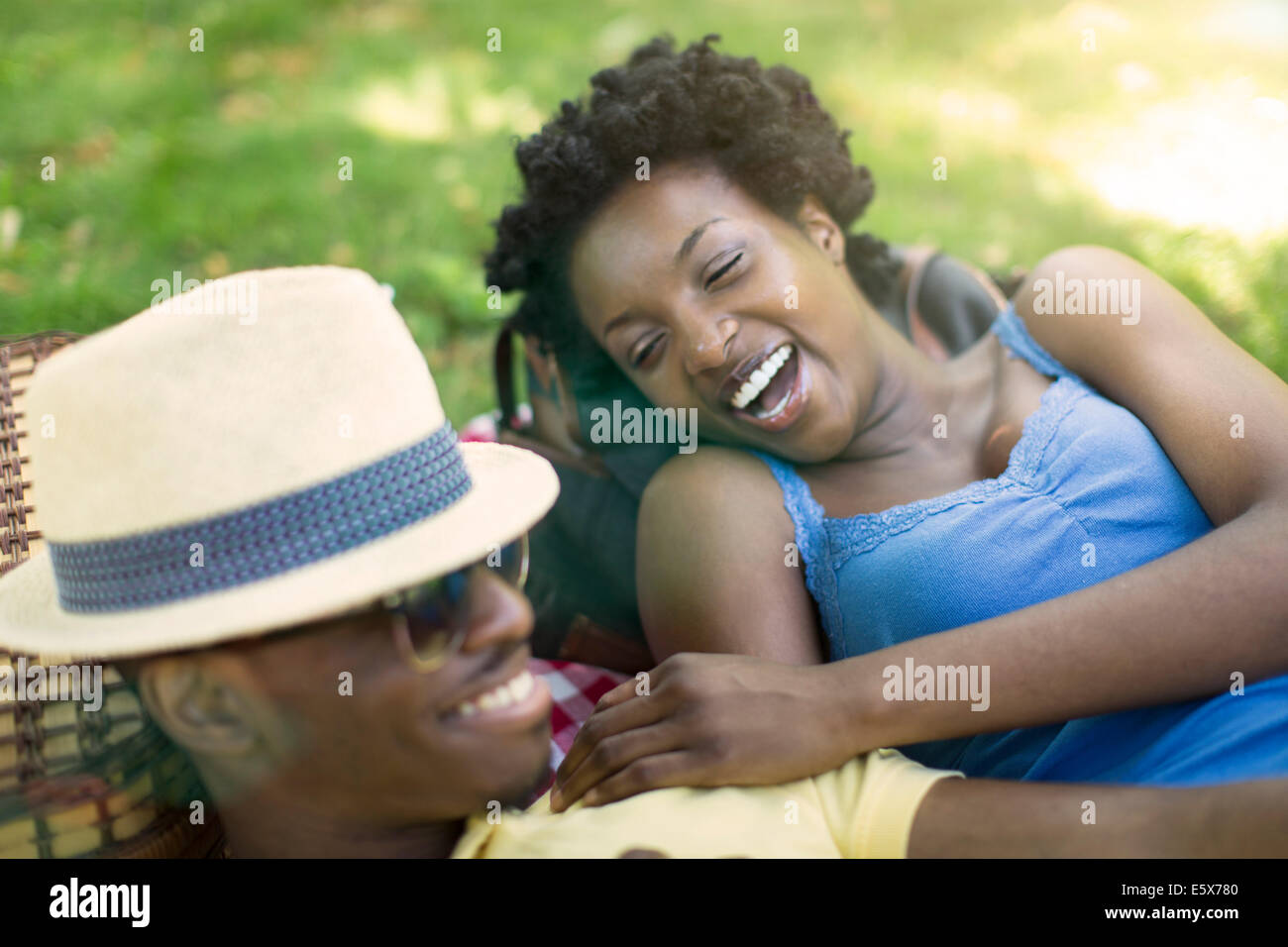 Young couple in lying in park laughing together Stock Photo - Alamy