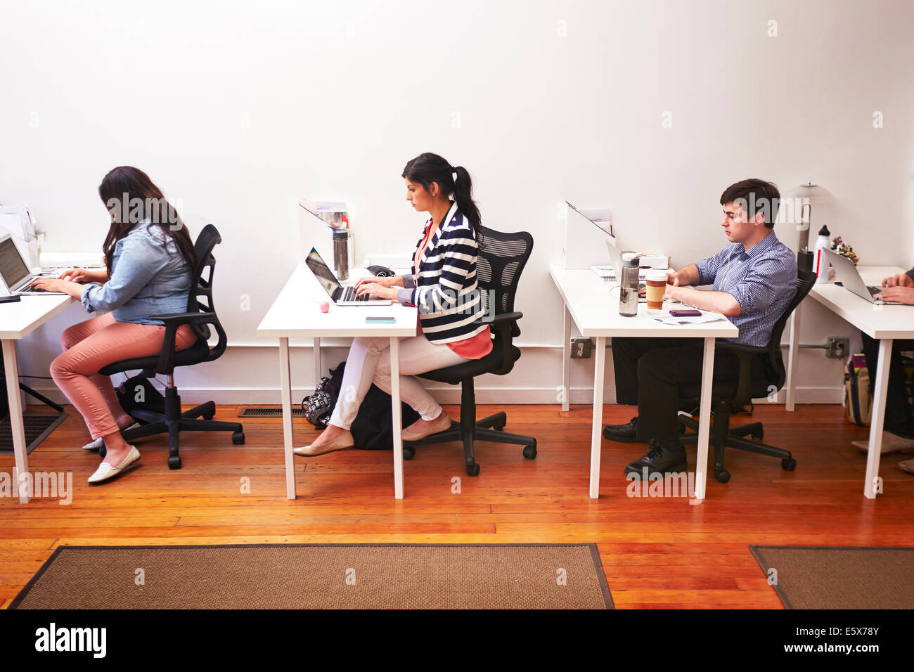 Row of people working at desks in office Stock Photo