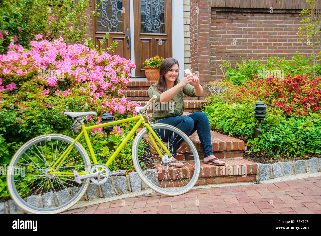 Young woman taking self portrait on smartphone on house steps Stock Photo