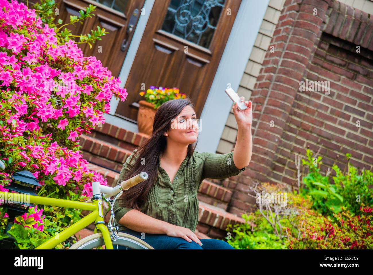 Young woman taking selfie on smartphone on house steps Stock Photo