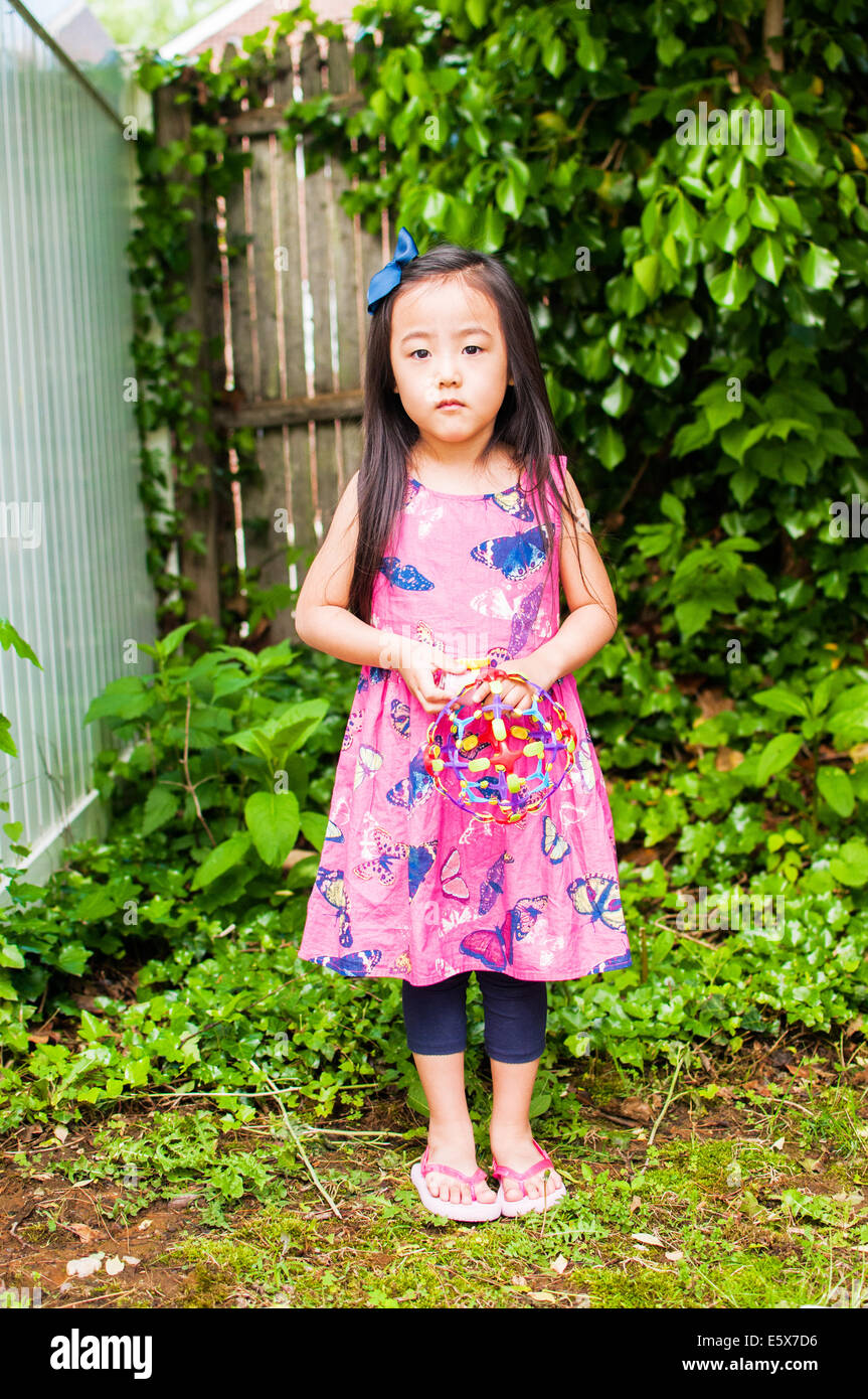 Portrait of serious young girl in garden with toy Stock Photo