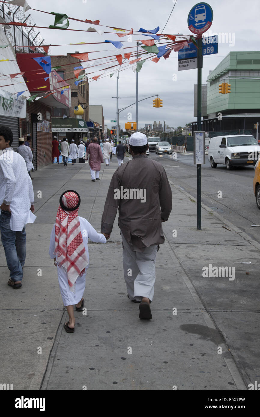 Father and small son walk to morning prayers in Kensington, Brooklyn, NY on the holiday of Eid at the end of Ramadan. Stock Photo