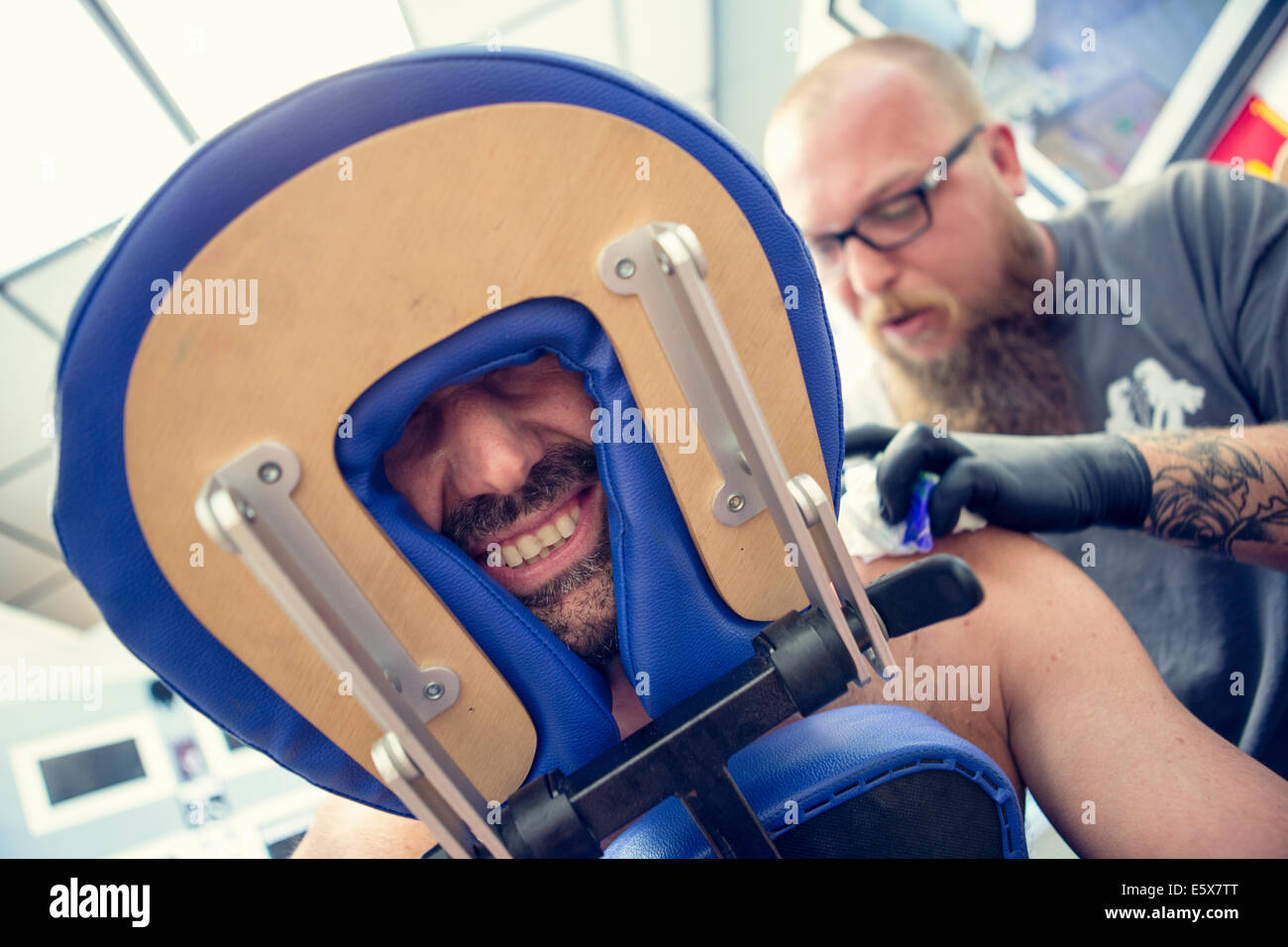 Male customers face between headrest in tattoo parlor Stock Photo