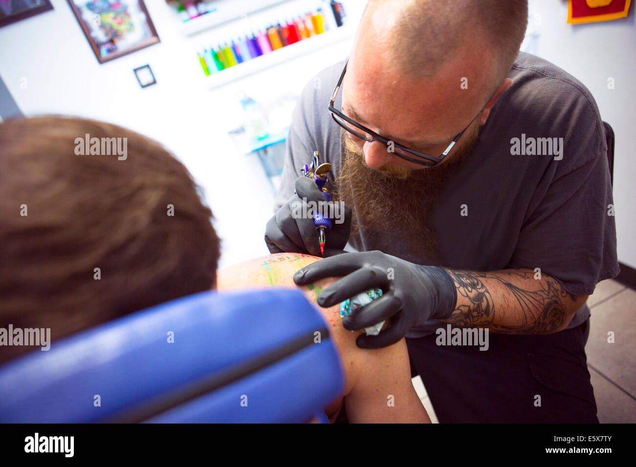 Mid adult man having shoulder tattooed in tattoo parlor Stock Photo