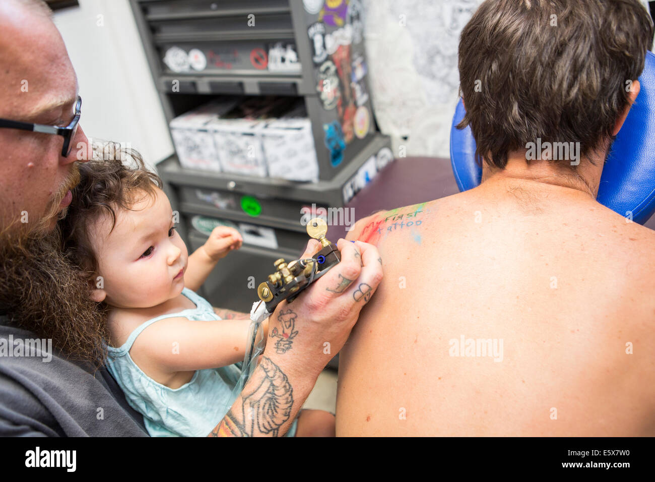 Tattoo artist showing toddler how to give a tattoo Stock Photo